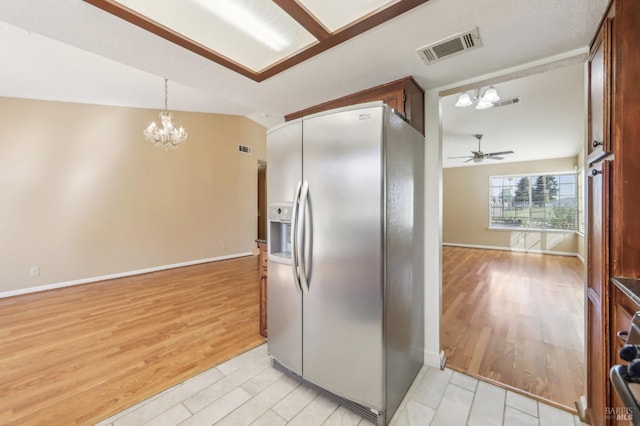 kitchen featuring vaulted ceiling, stainless steel fridge, ceiling fan with notable chandelier, visible vents, and light wood-style floors