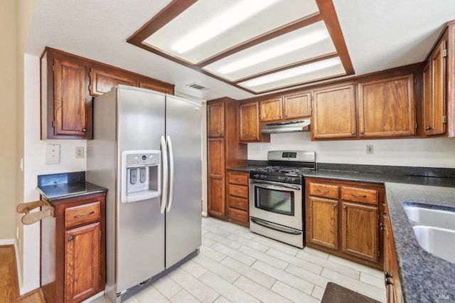 kitchen with under cabinet range hood, visible vents, brown cabinets, and stainless steel appliances