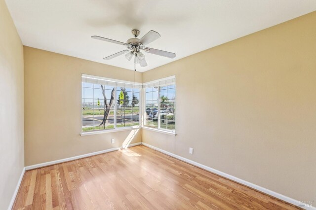 spare room with baseboards, wood finished floors, and a ceiling fan
