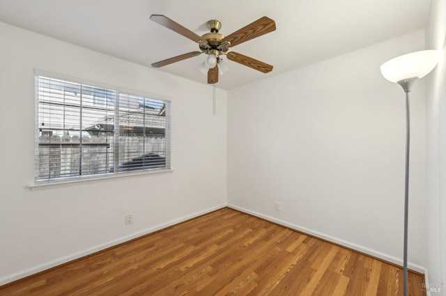 empty room featuring baseboards, wood finished floors, and a ceiling fan