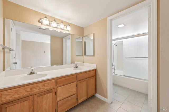 full bathroom with tile patterned flooring, a sink, double vanity, and bath / shower combo with glass door