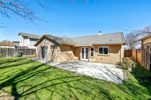 back of property featuring stucco siding, a fenced backyard, a tiled roof, a yard, and a patio area