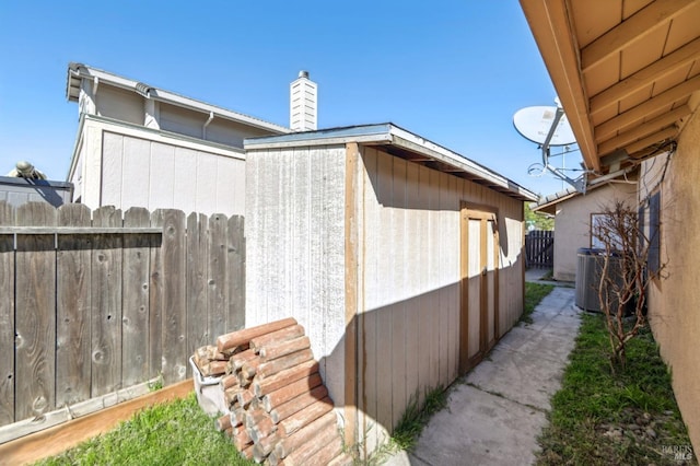 view of side of property featuring central air condition unit, a chimney, and fence