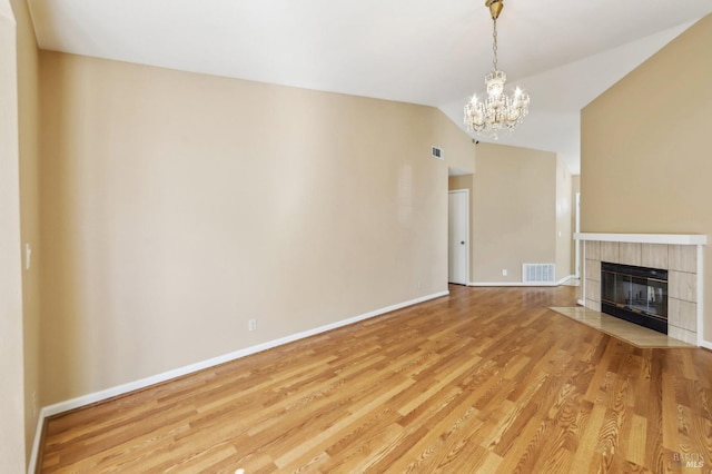 unfurnished living room featuring vaulted ceiling, a notable chandelier, light wood finished floors, and visible vents