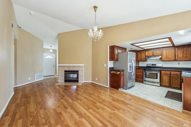 kitchen with lofted ceiling, under cabinet range hood, dark countertops, visible vents, and appliances with stainless steel finishes