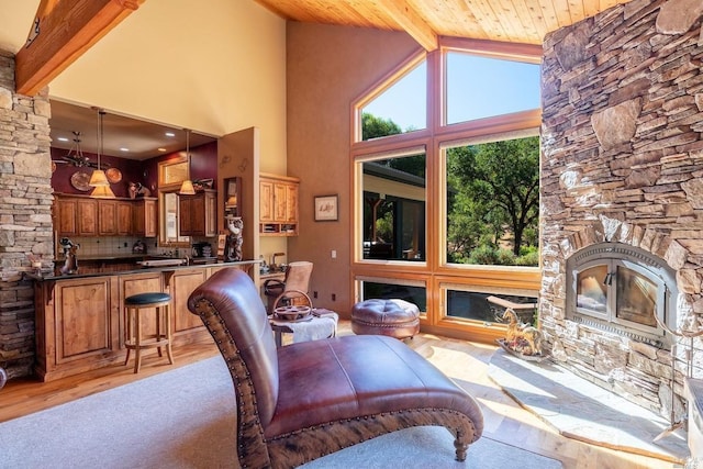 living room featuring high vaulted ceiling, a stone fireplace, beam ceiling, and light wood finished floors