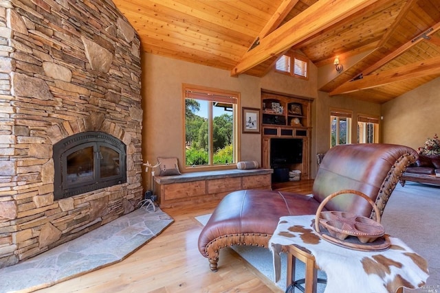 living area featuring lofted ceiling with beams, a fireplace, wood finished floors, and wooden ceiling