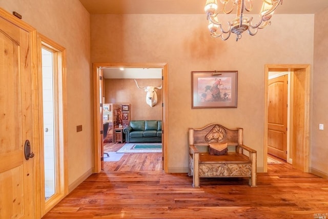 foyer entrance with baseboards, a notable chandelier, and wood finished floors