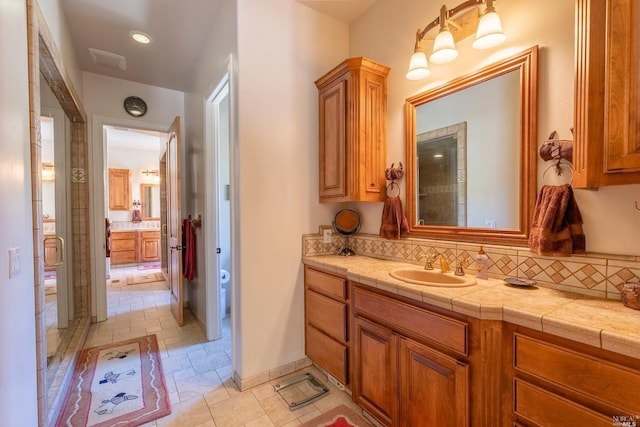 full bathroom with a shower stall, vanity, and tasteful backsplash