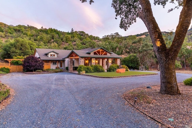 view of front of property featuring gravel driveway, a forest view, and fence