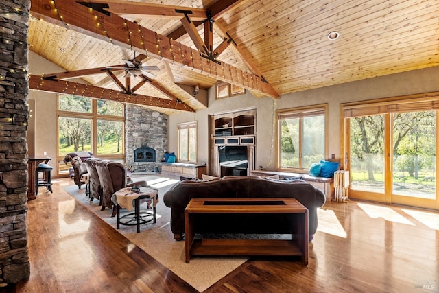 living area featuring wood ceiling, a stone fireplace, a healthy amount of sunlight, and wood finished floors
