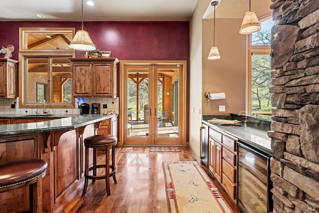 kitchen featuring decorative backsplash, brown cabinetry, light wood finished floors, and beverage cooler