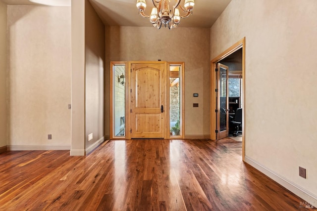 entryway with baseboards, wood finished floors, and a notable chandelier