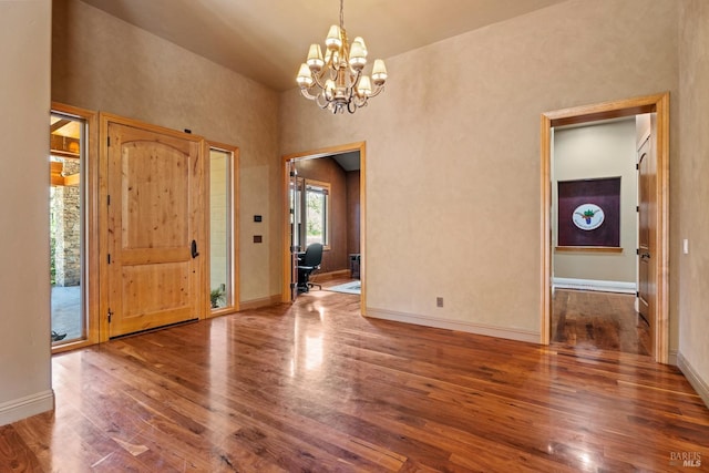 foyer featuring baseboards, a notable chandelier, and wood finished floors