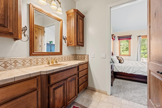 ensuite bathroom with vanity, baseboards, ensuite bath, and decorative backsplash