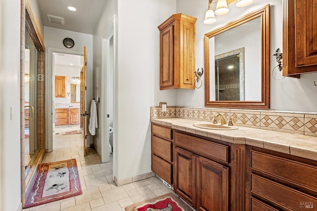 full bathroom with a shower stall, vanity, and backsplash