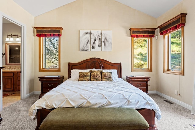 bedroom featuring lofted ceiling, carpet, baseboards, ensuite bath, and visible vents