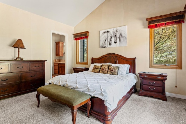 carpeted bedroom with baseboards, lofted ceiling, and ensuite bath