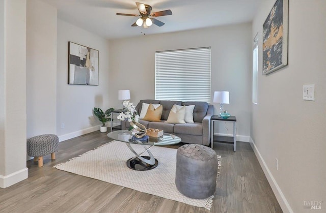 living area featuring baseboards, ceiling fan, and wood finished floors