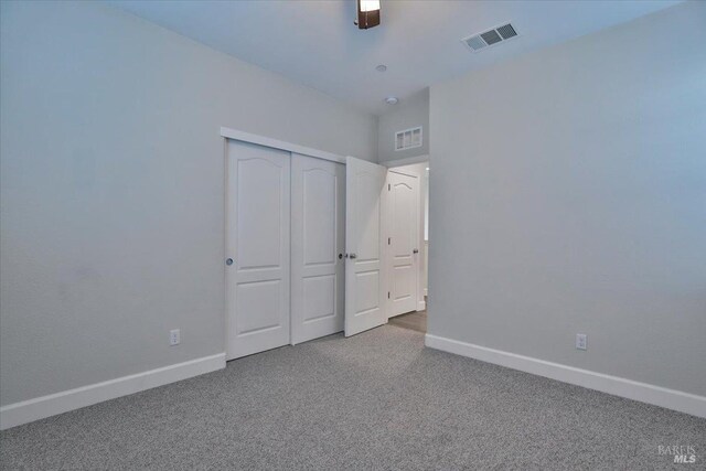 unfurnished bedroom featuring baseboards, carpet flooring, visible vents, and a closet