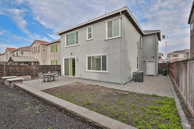 back of house featuring cooling unit, a fenced backyard, stucco siding, and a patio