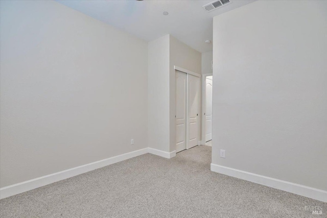 empty room with baseboards, visible vents, and light carpet