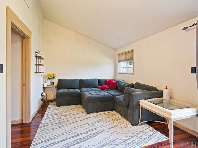 living room featuring dark wood-type flooring, baseboards, and vaulted ceiling