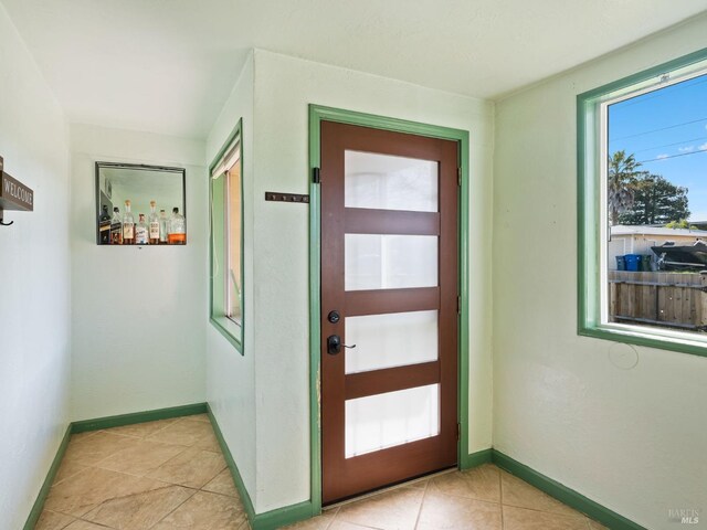 foyer featuring baseboards and light tile patterned flooring