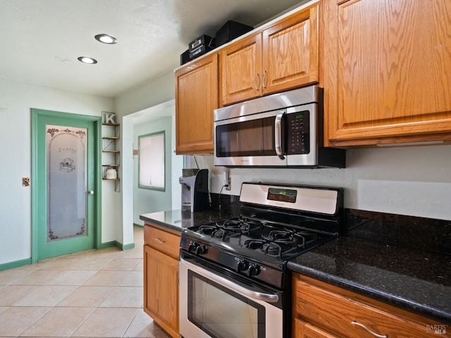 kitchen featuring light tile patterned floors, baseboards, appliances with stainless steel finishes, recessed lighting, and dark stone counters