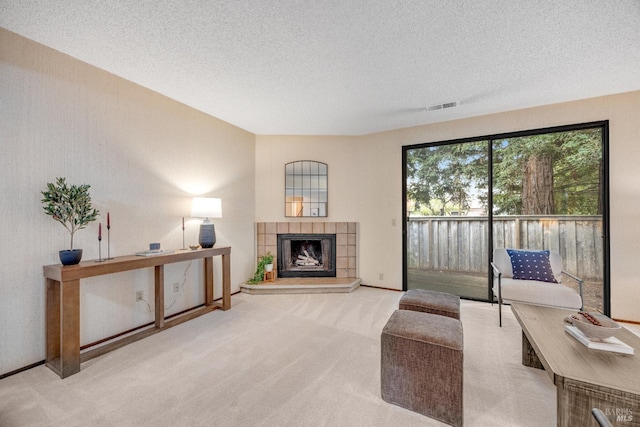 carpeted living area with a textured ceiling, visible vents, and a fireplace