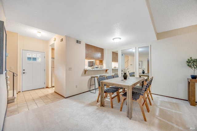 dining space featuring light tile patterned floors, light carpet, a textured ceiling, and visible vents