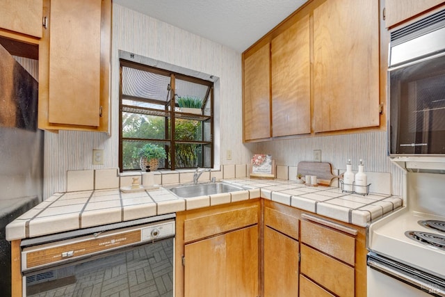 kitchen with wallpapered walls, a sink, tile countertops, white electric stove, and dishwasher
