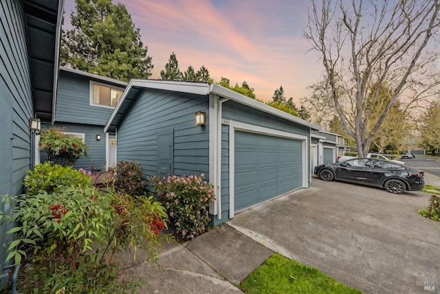 garage at dusk featuring concrete driveway