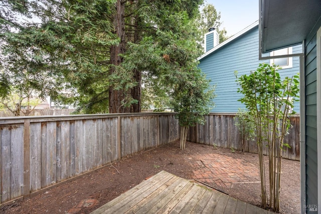 wooden deck with a fenced backyard and a patio