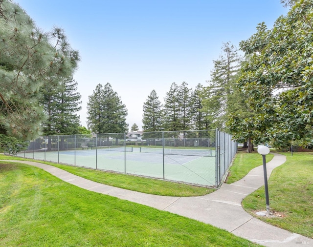 view of sport court with fence and a yard
