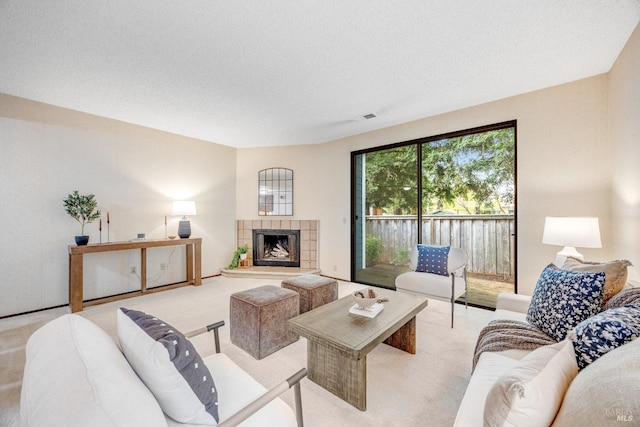 carpeted living area with visible vents, a tile fireplace, and a textured ceiling