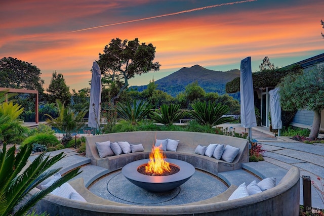 patio terrace at dusk with an outdoor living space with a fire pit and a mountain view