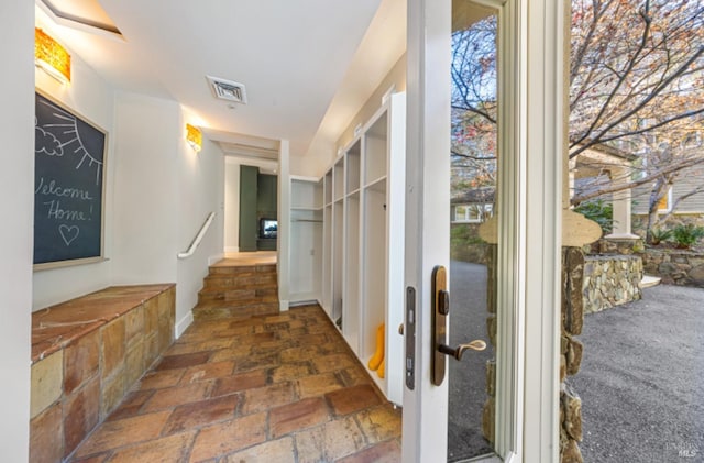 hall featuring stone tile floors and visible vents