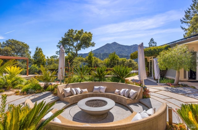 view of patio with an outdoor living space with a fire pit and a mountain view