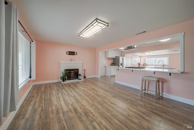 900 5th St, Fairfield, CA 94533 - unfurnished living room with a glass covered fireplace, baseboards, visible vents, a sink, and wood finished floors
