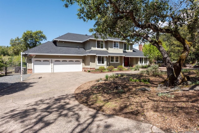 view of front of house featuring driveway, a garage, fence, and a shingled roof