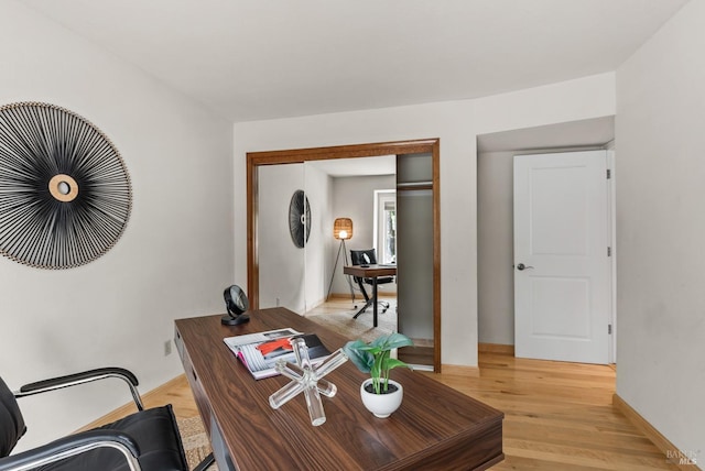 home office with baseboards and light wood finished floors