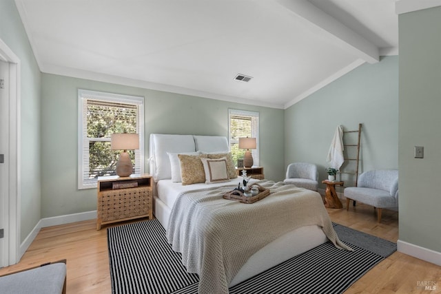 bedroom with lofted ceiling with beams, baseboards, multiple windows, and light wood-type flooring