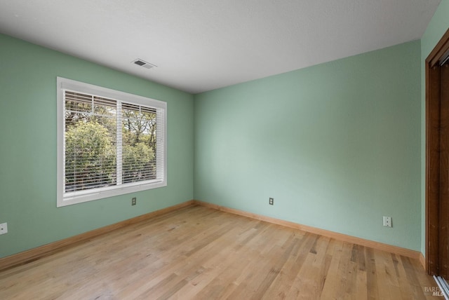 unfurnished room with baseboards, visible vents, and light wood-style floors