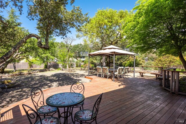 deck featuring a gazebo, fence, and outdoor dining space
