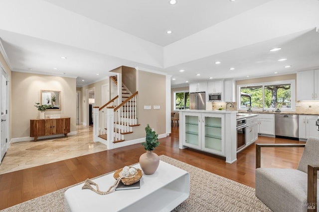 living room with stairs, recessed lighting, ornamental molding, baseboards, and light wood-style floors