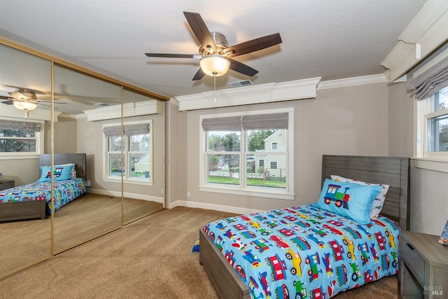 carpeted bedroom featuring crown molding, a closet, baseboards, visible vents, and ceiling fan