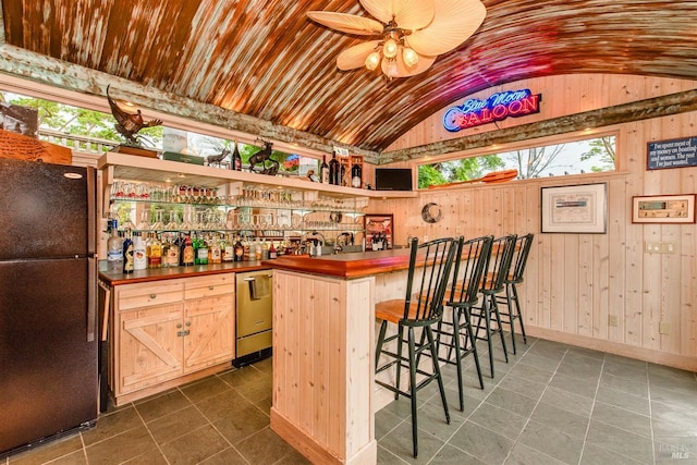 bar featuring dishwasher, ceiling fan, indoor wet bar, vaulted ceiling, and freestanding refrigerator
