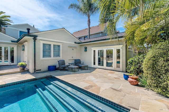 rear view of house featuring stucco siding, an outdoor pool, french doors, and a patio area