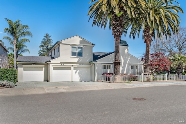 view of front of home featuring driveway, a garage, and fence